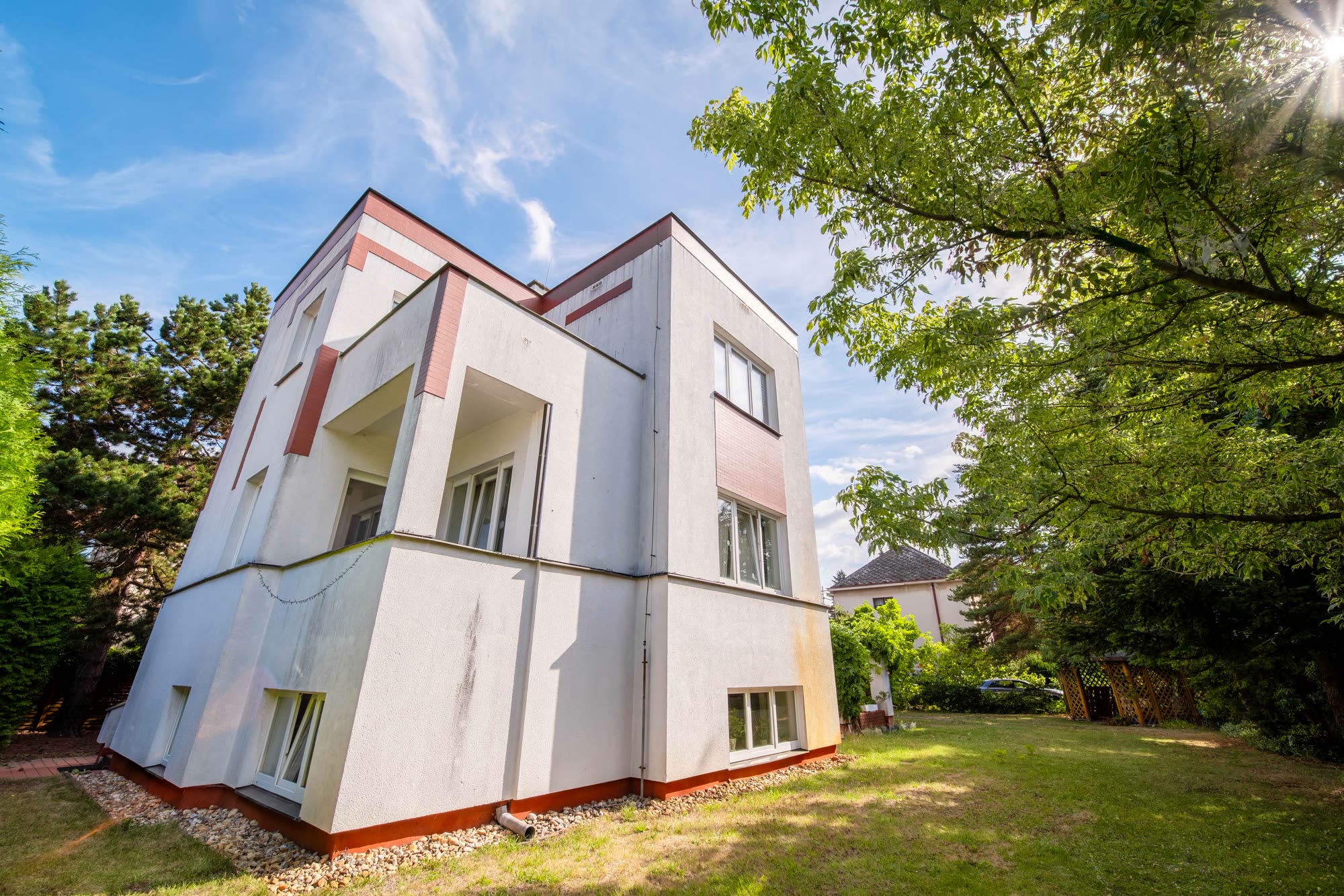 Detailní pohled na nároží domu s lodžiemi a světlou fasádou.